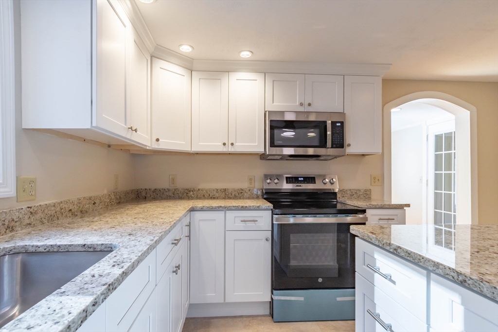 137 Lowell Road Pepperell, MA 01463 - Photo 6 of 40 a kitchen with granite countertop a stove top oven microwave and cabinets