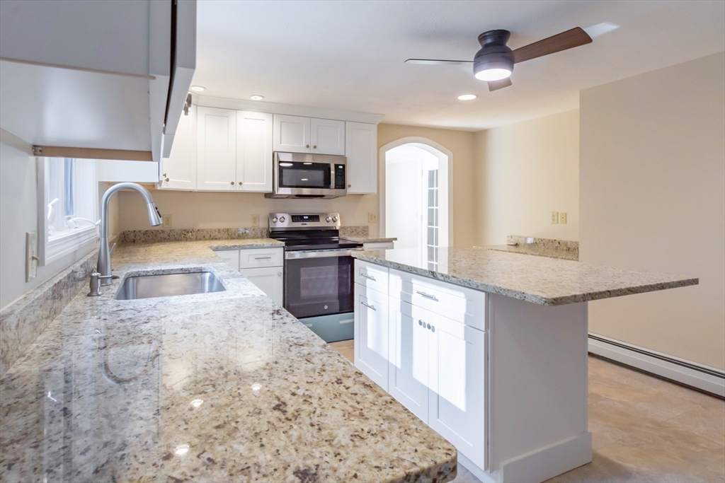 137 Lowell Road Pepperell, MA 01463 - Photo 9 of 40 a large kitchen with stainless steel appliances granite countertop a sink a stove top oven a counter space and cabinets