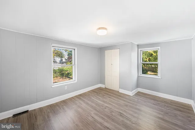 an empty room with wooden floor and windows
