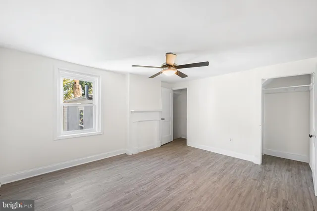 an empty room with wooden floor and a ceiling fan