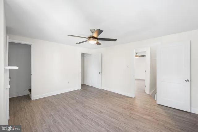 an empty room with wooden floor ceiling fan and windows
