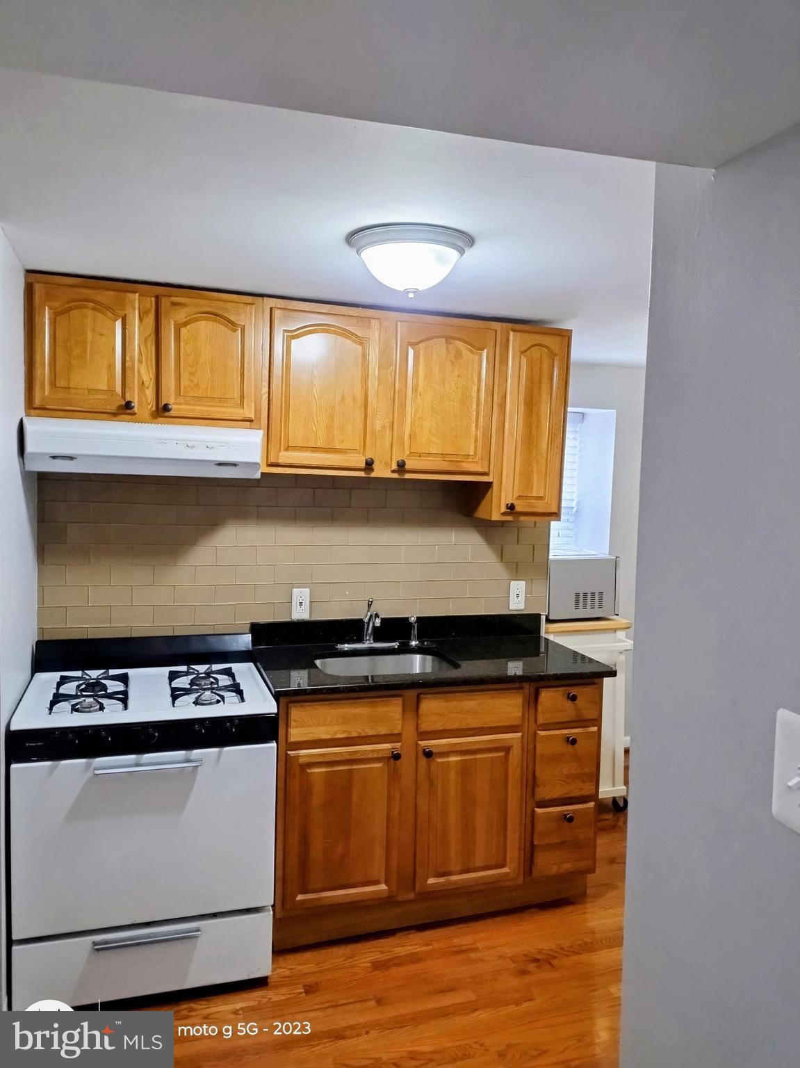 2437 Grays Ferry Avenue, Unit 3 Philadelphia, PA 19146 - Photo 9 of 15 a kitchen with granite countertop a stove a sink and a microwave