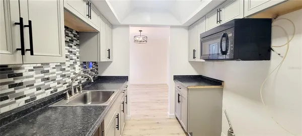 a kitchen with granite countertop a sink stove and microwave