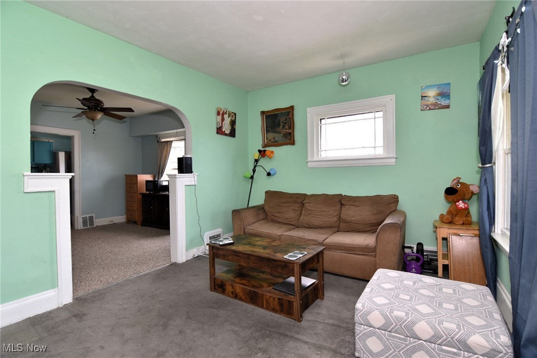 4213 Valley Road Cleveland, OH 44109 - Photo 20 of 47 Carpeted living room featuring ceiling fan, a fireplace, arched walkways, visible vents, and baseboards