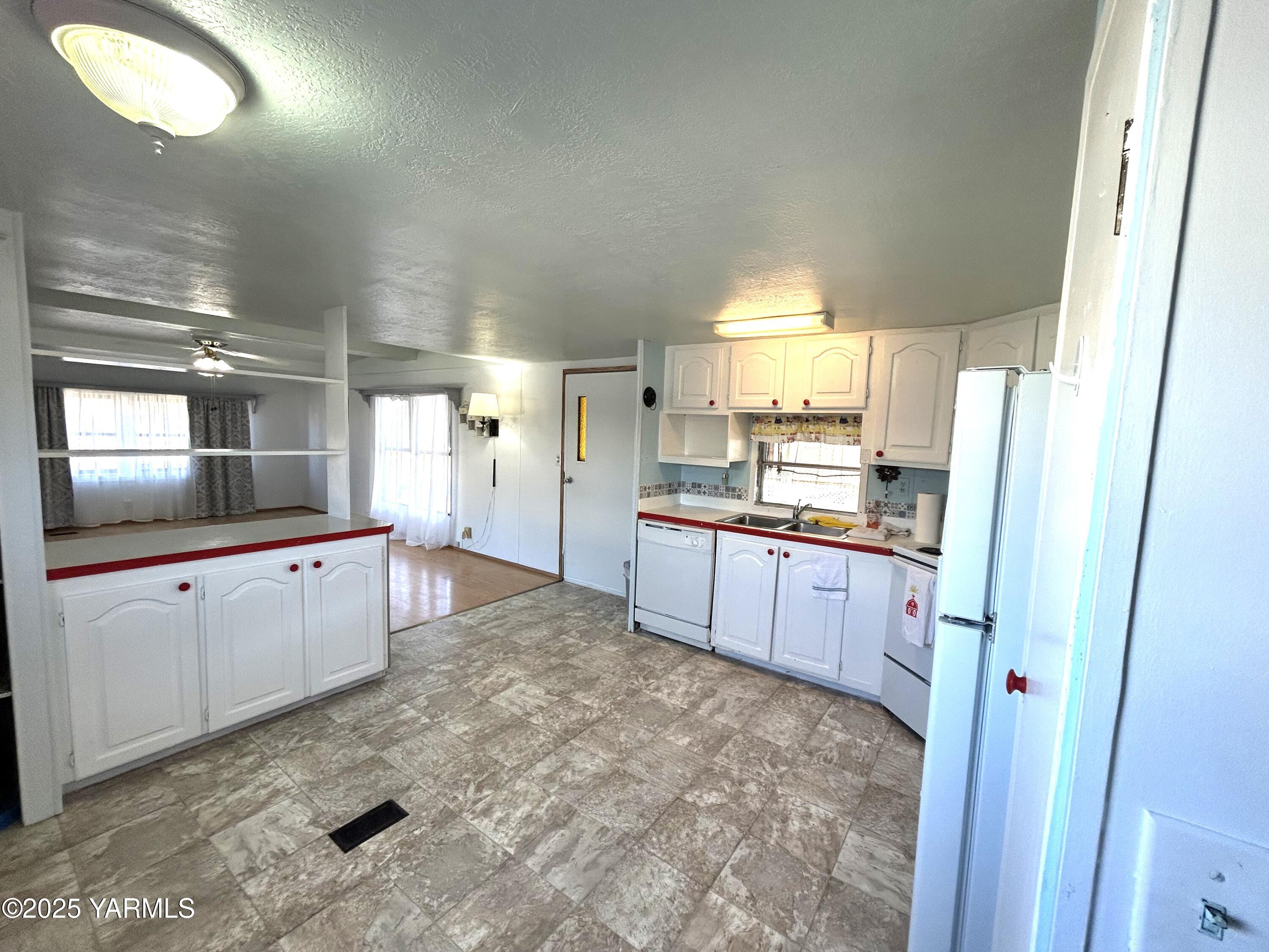 451 Pence Road, Unit 49 Yakima, WA 98908 - Photo 10 of 16 a large kitchen with kitchen island granite countertop a refrigerator and white cabinets