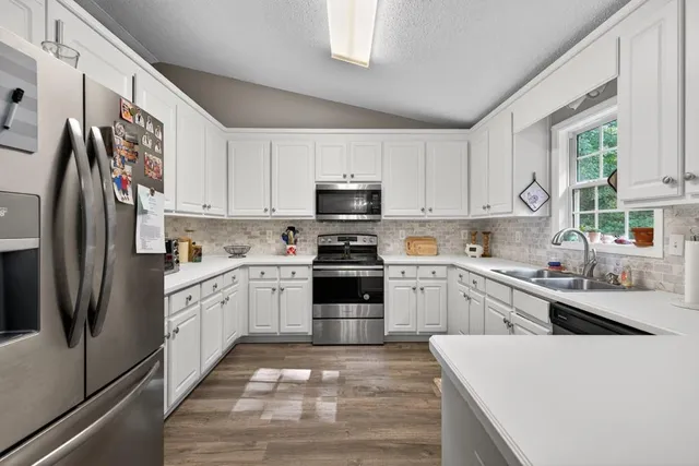 a kitchen with granite countertop white cabinets and stainless steel appliances