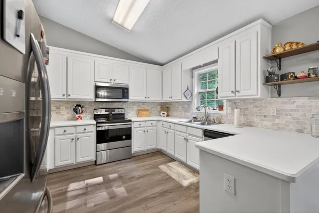 a kitchen with white cabinets and appliances
