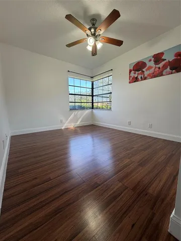 a view of empty room with wooden floor and fan
