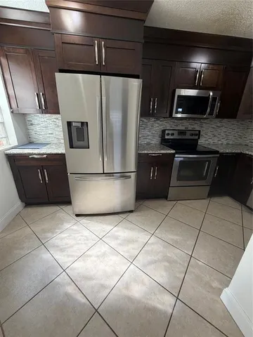 a kitchen with granite countertop a refrigerator and a sink