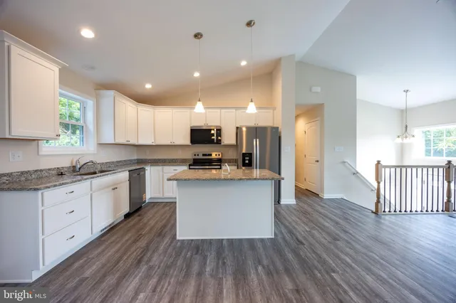 a kitchen with stainless steel appliances granite countertop wooden floors and white cabinets