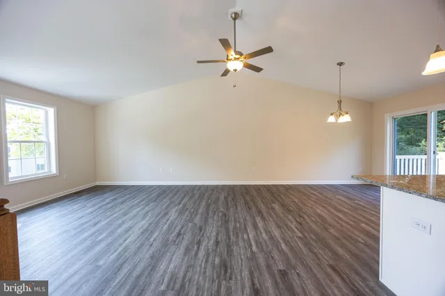 an empty room with wooden floor fan and windows