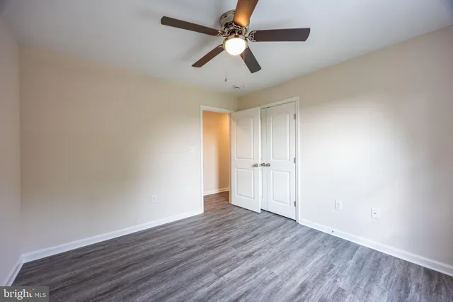 an empty room with wooden floor ceiling fan and windows