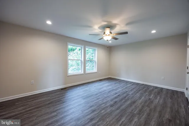 an empty room with wooden floor and a ceiling fan