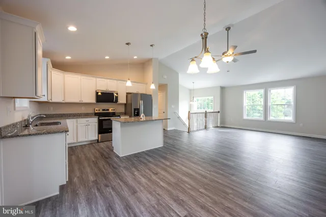 a large kitchen with cabinets wooden floor and stainless steel appliances