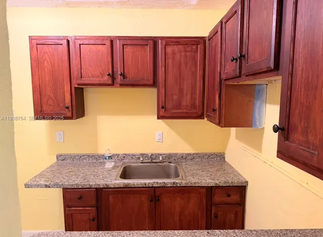 a kitchen with granite countertop a sink a stove and a wooden cabinets