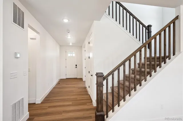 a view of staircase with lots of frames on wall and wooden floor