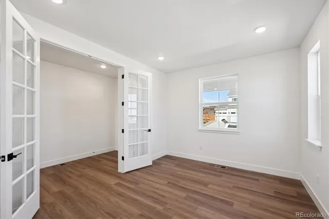 an empty room with wooden floor and windows