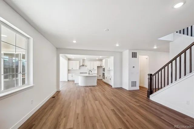 a view of a living room hardwood floor and a kitchen with wooden floor