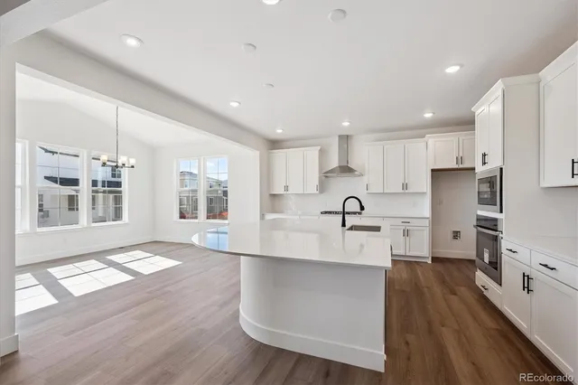 a large white kitchen with lots of counter space wooden floor and stainless steel appliances
