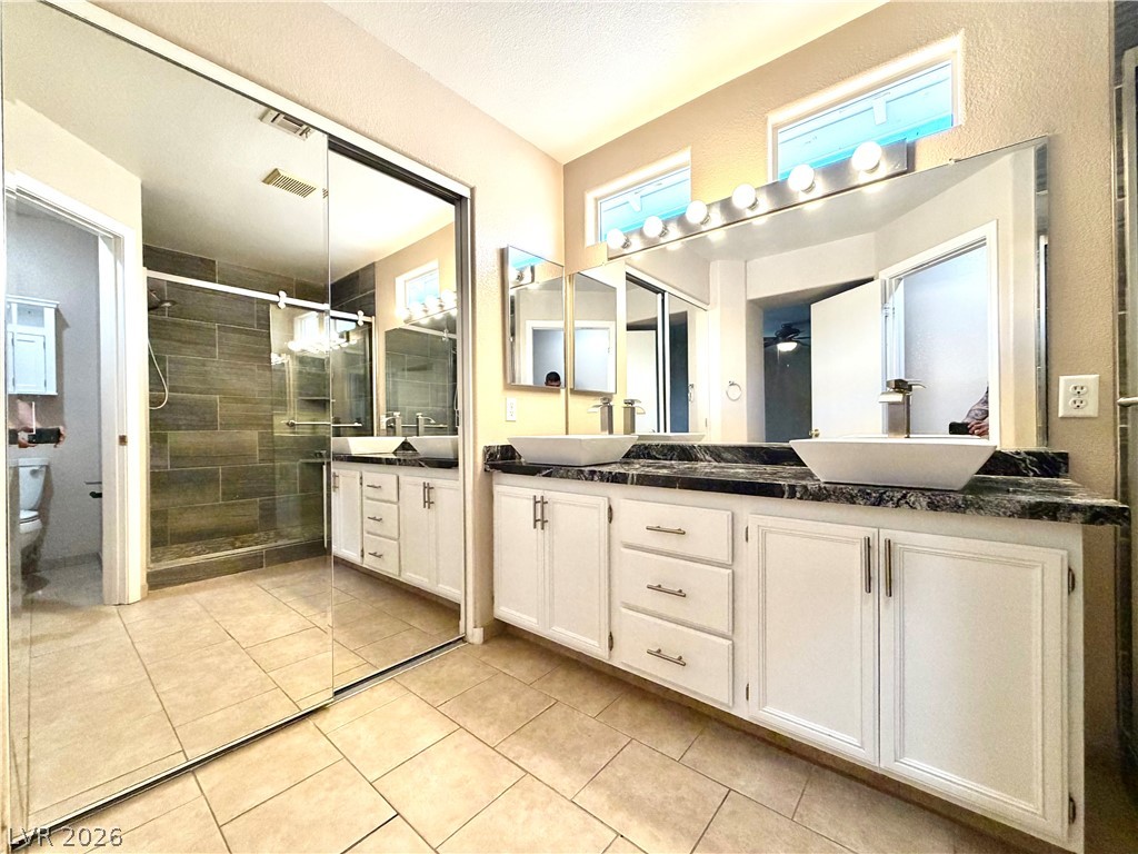 3936 Gold Point Street Las Vegas, NV 89129 - Photo 12 of 23 Dual vanity sinks and a spacious walk-in shower elevate this contemporary bathroom.