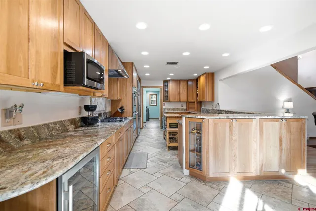 a large kitchen with stainless steel appliances granite countertop a sink and cabinets