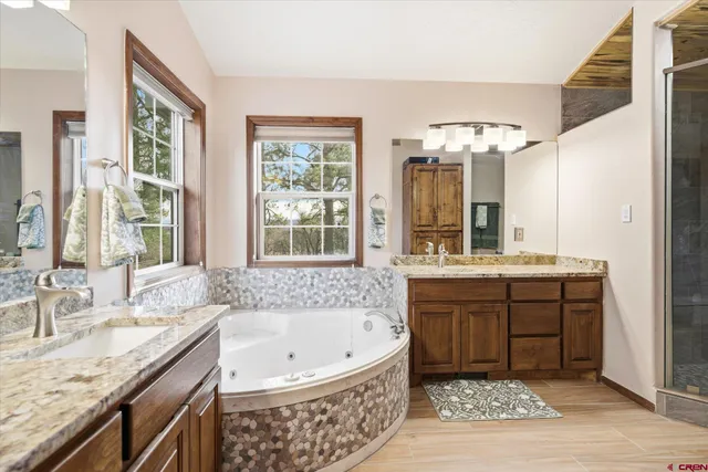 a bathroom with a granite countertop tub sink and mirror