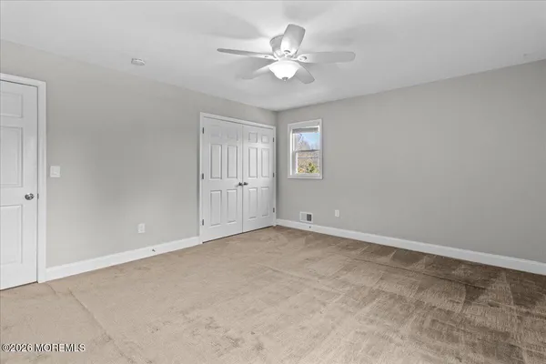 an empty room with windows and ceiling fan
