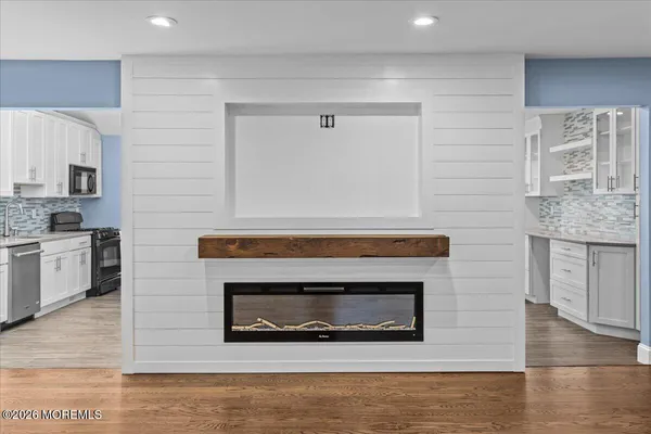 a living room with stainless steel appliances wooden floor and a fireplace