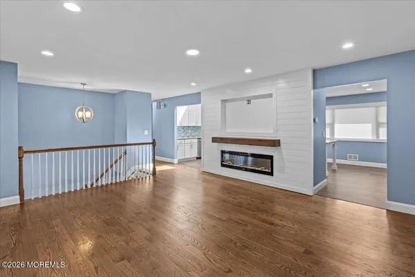 an empty room with wooden floor fireplace and windows