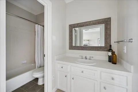 a bathroom with a granite countertop toilet a sink a mirror and a shower