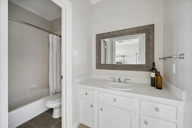 a bathroom with a granite countertop toilet a sink a mirror and a shower