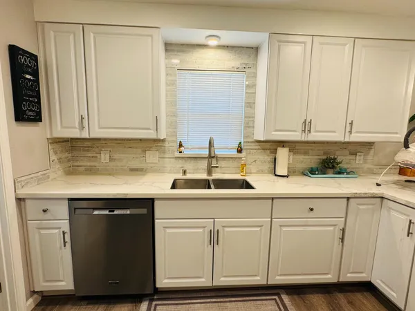 a kitchen with white cabinets and sink
