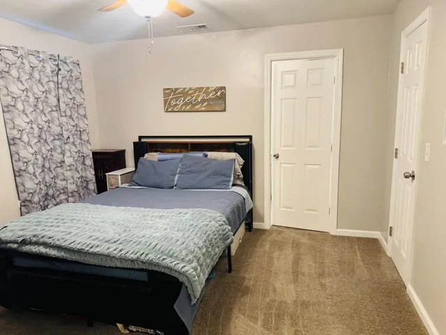a bedroom with a large bed and ceiling fan