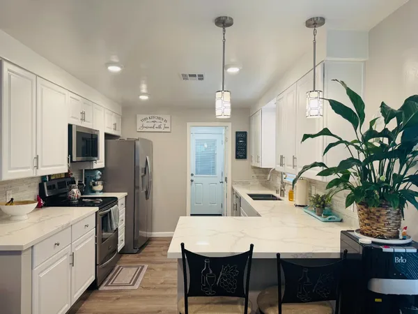 a kitchen with stainless steel appliances a dining table chairs stove refrigerator and microwave