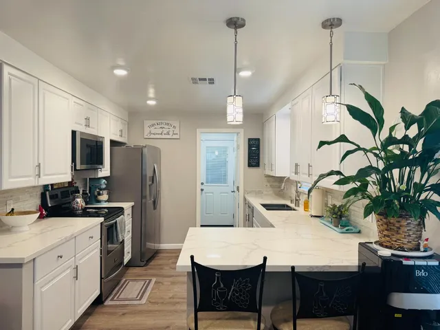 a kitchen with stainless steel appliances a dining table chairs stove refrigerator and microwave