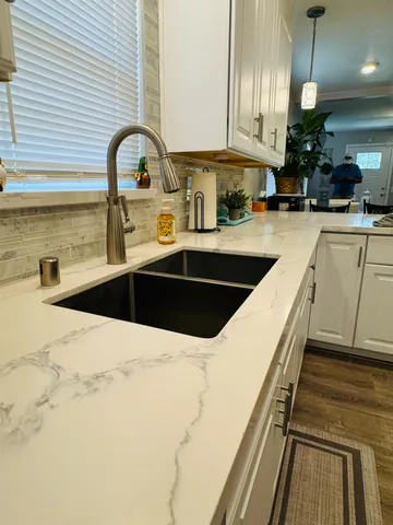a kitchen with white cabinets a sink and dishwasher