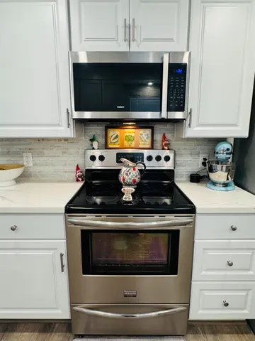a kitchen with microwave a stove and cabinets
