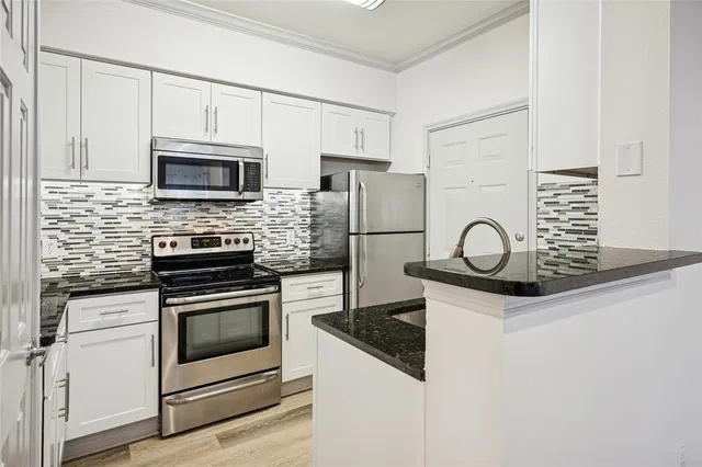 a kitchen with granite countertop white cabinets stainless steel appliances and sink