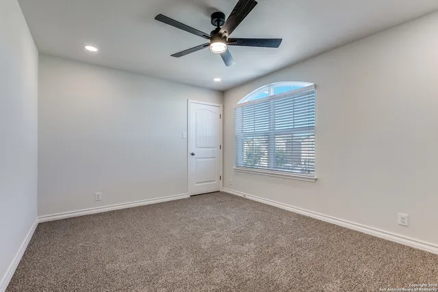 an empty room with a ceiling fan and window
