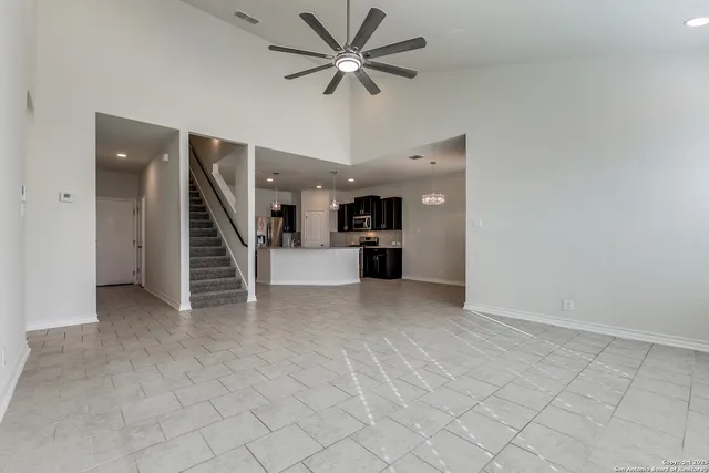 an empty room with windows and ceiling fan