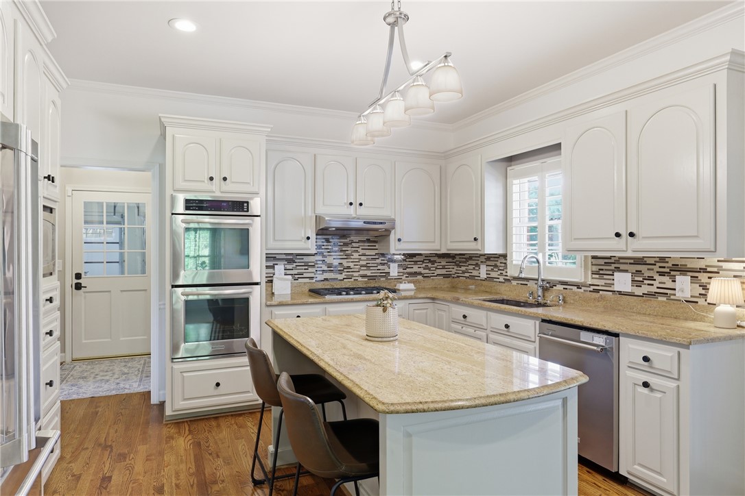 103 5 Knoll Court Anderson, SC 29621 - Photo 8 of 33 A chef's kitchen showcasing light-toned cabinetry, granite countertops, and wood flooring.