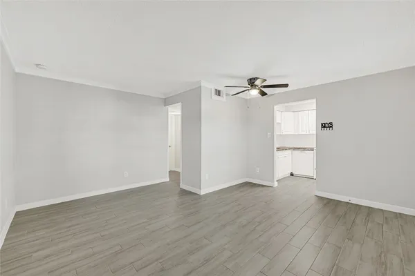 a view of empty room with wooden floor and fan