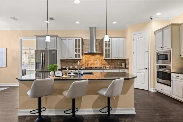 a large kitchen with stainless steel appliances kitchen island granite countertop wooden floors a sink and a granite counter tops