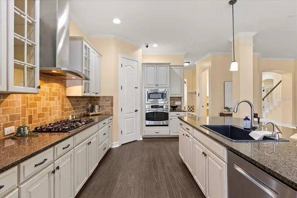 a kitchen with stainless steel appliances granite countertop a stove refrigerator and chairs