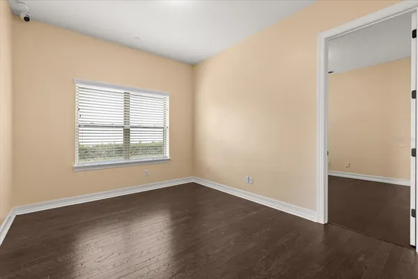 an empty room with wooden floor and windows