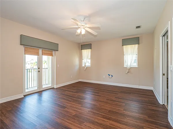 an empty room with wooden floor and windows