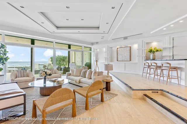 a living room with furniture large windows and wooden floor