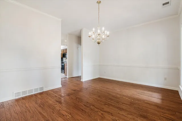 a view of empty room with wooden floor and chandelier
