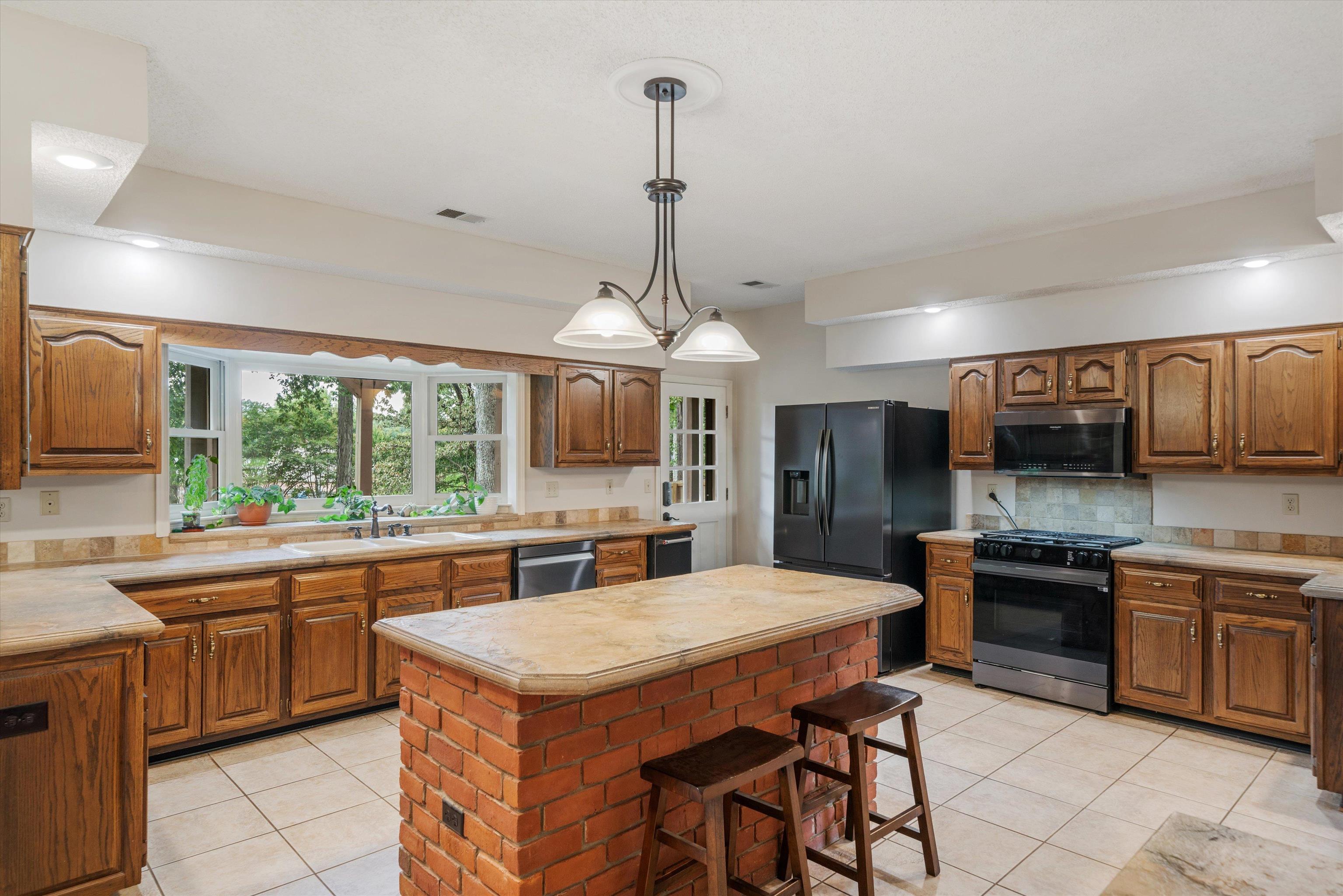 4309 Garner Place Bartlett, TN 38135 - Photo 7 of 40 a kitchen with a stove a sink a kitchen island with chairs and wooden cabinets