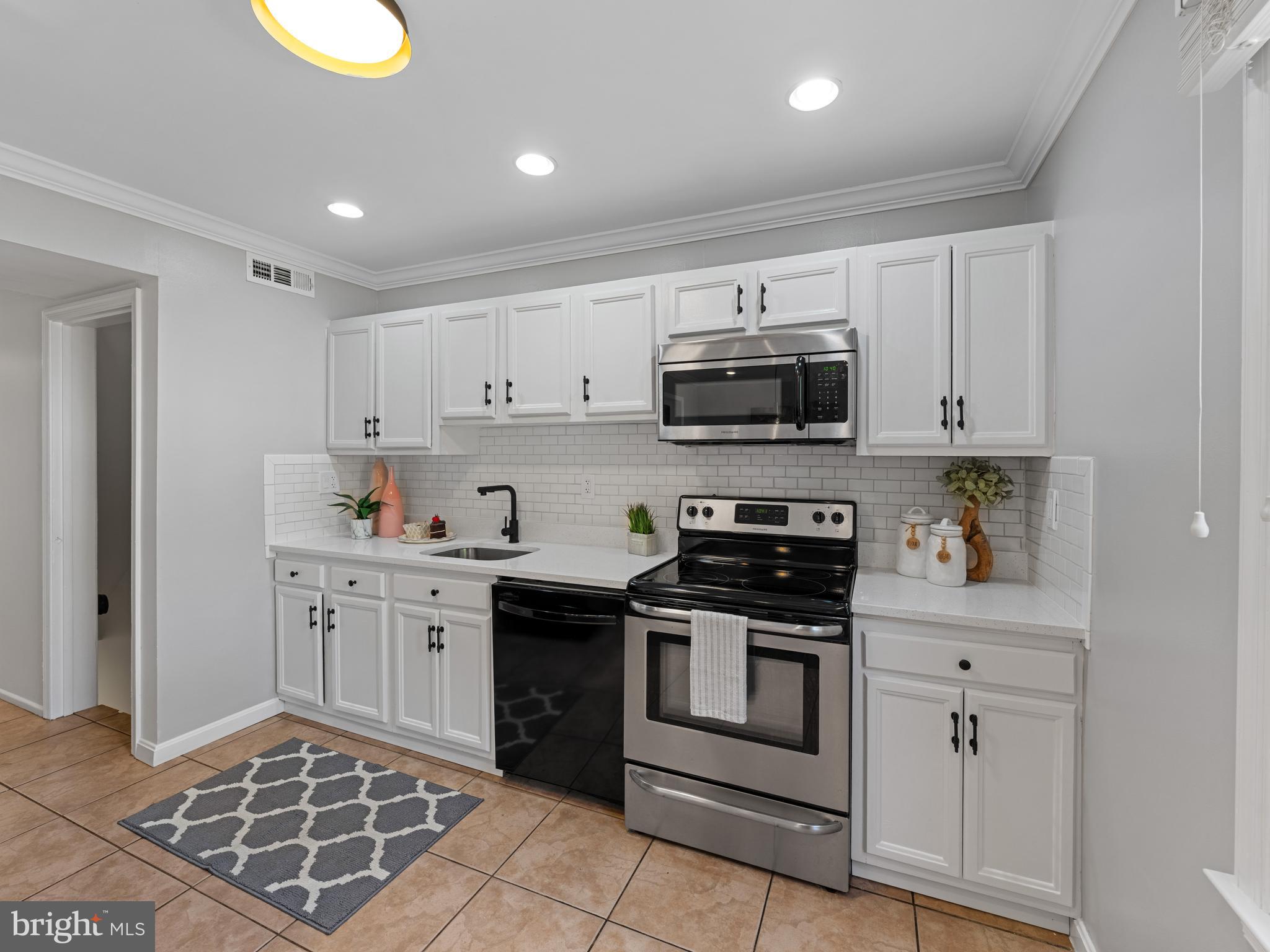 8448 Kitchener Drive Springfield, VA 22153 - Photo 12 of 32 a kitchen with stainless steel appliances granite countertop a stove a sink and a microwave